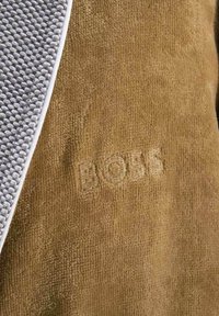 Brauner Stoff mit weicher Textur zeigt einen grauen, gemusterten Akzent. Das gestickte Logo "BOSS" ist auf dem braunen Material sichtbar.