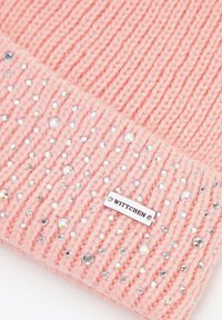 Różowa dzianinowa czapka o prążkowanej fakturze, ozdobiona przezroczystymi cyrkoniami i srebrną metką z napisem "WITTCHEN".