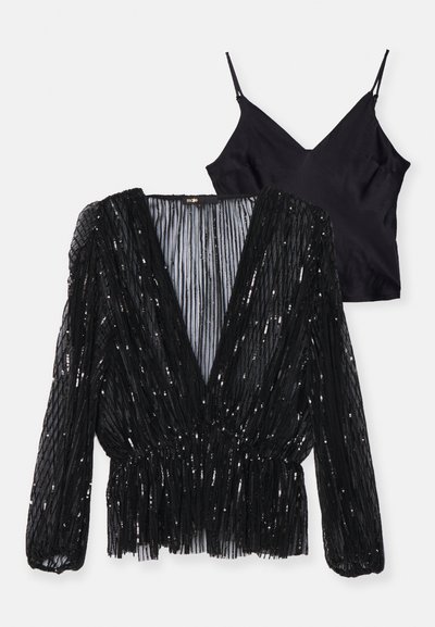 Top noir à manches longues avec des plis verticaux et des sequins, présentant un décolleté en V profond. Caraco noir attaché avec des bretelles fines et un décolleté en V.
