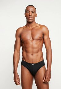 Slip en coton noir avec une coupe ajustée, doté d'une taille basse et d'un petit logo à l'avant. Texture lisse, design minimaliste.