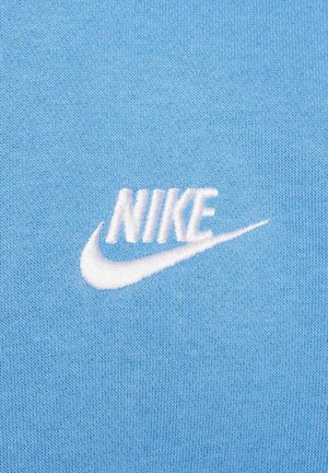 Niebieska bawełniana tkanina z haftowanym białym logo Nike w wyrazistym stylu, uzupełnionym akcentem w postaci znaku Swoosh. Tekstura gładka i miękka.