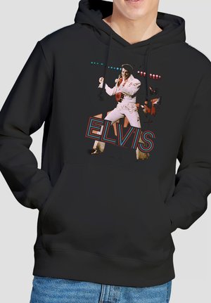Schwarzer Kapuzenpullover mit einer Grafik eines männlichen Sängers in weißem Outfit, der mit einem Mikrofon auftritt, und dem Wort "ELVIS" in stilisierten Buchstaben.