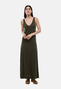 Robe maxi à bretelles spaghetti de couleur vert olive avec un décolleté en V profond, en tissu doux, présentant une coupe décontractée et un ourlet long.