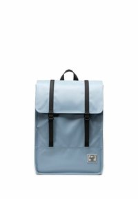 Sac à dos bleu clair avec un rabat, doté de sangles et de boucles en cuir noir. Comprend une petite poche avant avec un logo de marque. Matériau durable.