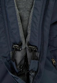 Gros plan sur le col d'une veste bleu marine avec une doublure en polaire grise et des coulisseaux noirs réglables sur les cordons.