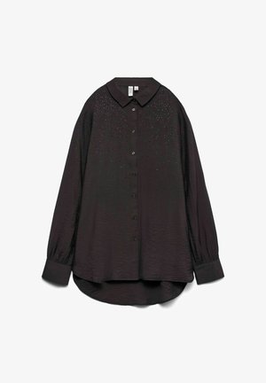 Langermet, mørk svart skjorte med krage, teksturert stoff og små dekorative nagler over øvre del foran.