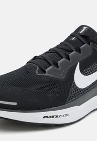 Chaussure de course Nike Air Zoom noire avec logo swoosh blanc, lacets noirs et tissu supérieur texturé et respirant.