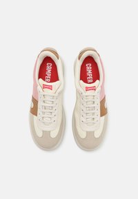 Beige Sneaker mit einem strukturierten Obermaterial, das pinke und braune Akzente aufweist. Schnürsenkel mit einer roten Innensohle und CAMPER-Branding. Gerundetes Zehen-Design.