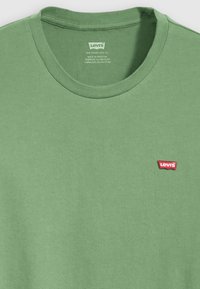 Groene katoenen t-shirt met een ronde hals, voorzien van een klein rood Levi's logo op de linkerborst. Glad textuur, casual ontwerp.