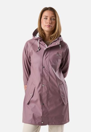 Woman wearing a mauve waterproof hooded raincoat with front snap buttons and flap pockets, standing against a plain background.