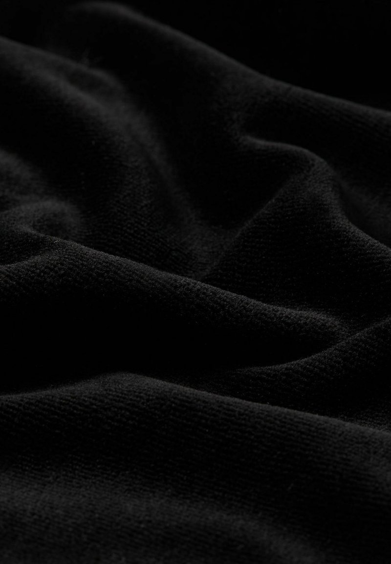 Schwarzer Stoff mit einer weichen, strukturierten Oberfläche, die sanfte Falten und Wellen zeigt und die Tiefe sowie die Farbintensität betont.