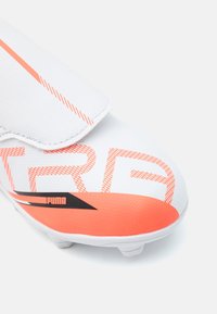 Crampon de football blanche avec des accents orange, dotée d'une tige texturée, d'un grand logo "PUMA" et d'un design léger pour des performances améliorées.