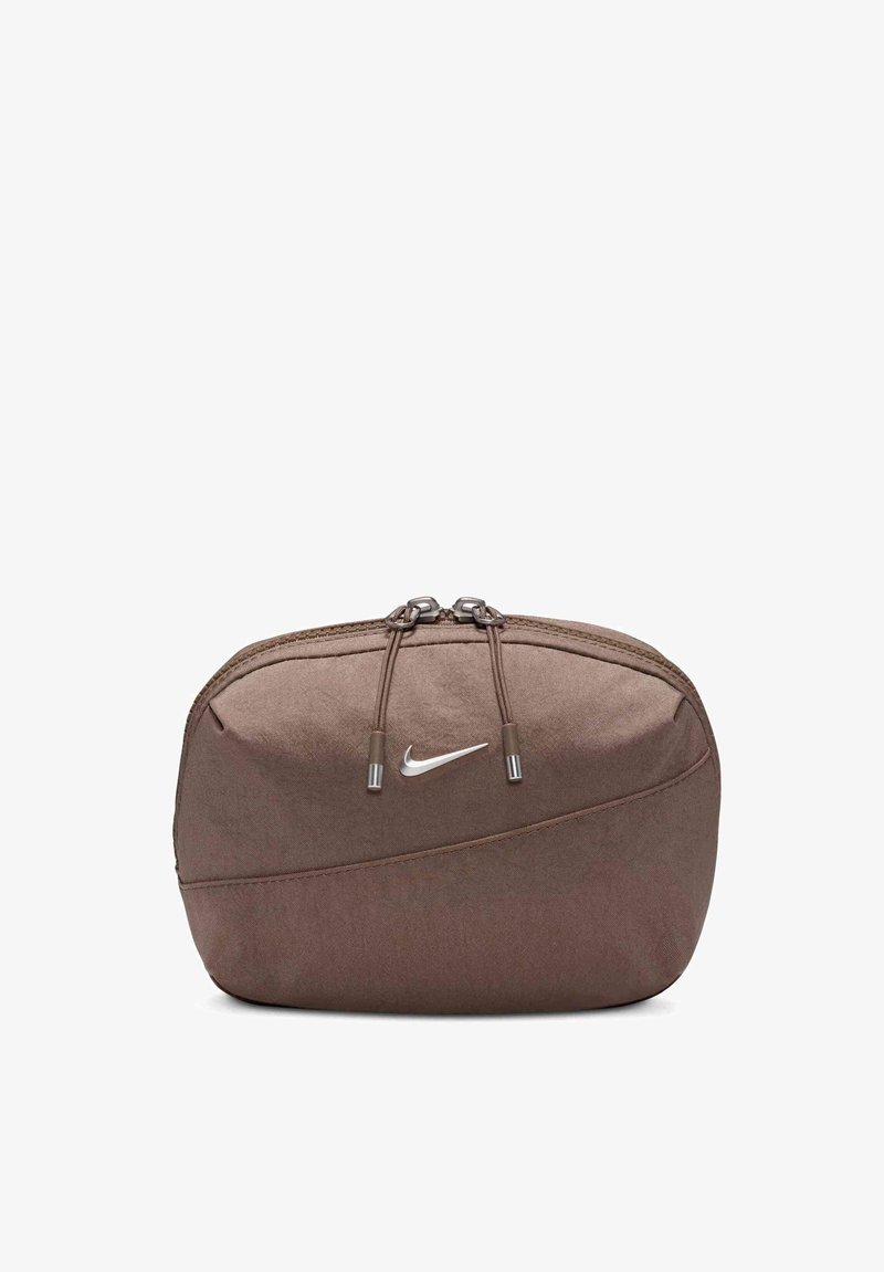 Hnedá taška Nike s hladkou textúrou, zipsovým uzatváraním a strieborným logom. Obsahuje sťahovacie šnúrky a elegantný zakrivený dizajn.