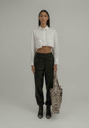 White cropped shirt, black leather pants, black pointed boots, holding a beige leopard print tote bag. Simple background, no additional details.
