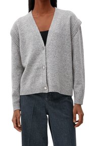 Ljusgrå kofta med v-ringning, ribbade kanter och tre silverknappar fram. Mjuk textur, oversized passform och korta ärmar.