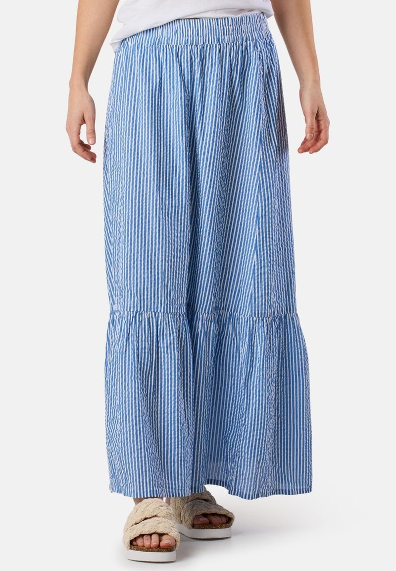 Maxikleid mit blauen und weißen Streifen, elastischem Bund, gerafften Lagen und einem leichten Stoff. Kombiniert mit flauschigen Sandalen.