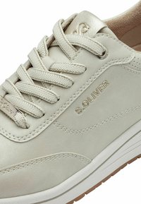 Baskets en cuir beige avec finition texturée, design à lacets, accents dorés et détail de logo. Présentent une semelle intérieure rembourrée et une semelle extérieure en caoutchouc.