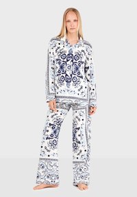 Weißes Schlafanzugset mit blauen Blumen- und Schmetterlingsmustern. Es umfasst ein Langarmoberteil mit Kragen und eine locker sitzende Hose. Glatte Stofftextur.