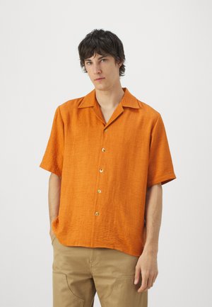 Kortærmet orange lin skjorte med knaplukning foran og spread krave. Har syv knapper og et tekstureret stof.