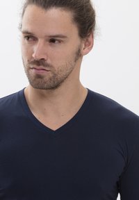 T-shirt col en V bleu marine fabriqué en tissu doux et lisse, présentant un design ajusté et des coutures minimales pour un look épuré.