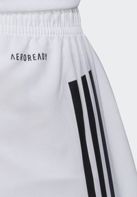 Pantaloni corti bianchi con vita elasticizzata, logo "AEROREADY" in nero e tre strisce verticali nere sui lati. Tessuto testurizzato.