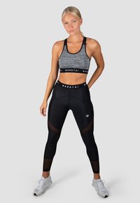 Sportbh in grijze en zwarte stof met een brede zwarte band met de tekst "MOROTAI." Zwarte leggings met meshpanelen en een wit logo op de heup.