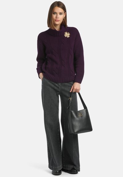 Pulover tricotat violet cu guler înalt, asortat cu blugi gri cu picioare largi. Geantă neagră cu un detaliu de logo auriu.