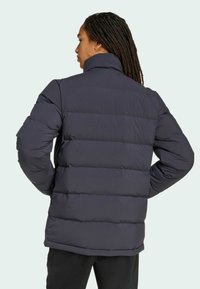 Navy puffer jacket with a high collar, featuring horizontal quilting and a relaxed fit. The fabric is smooth, providing insulation.
