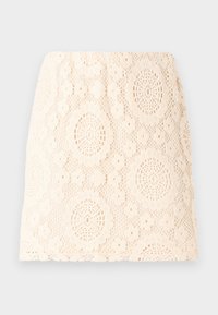 Lacekjol i krämvit med ett blommönster. Har intrikata ovala utskärningar och en figursydd silhuett. Den texturerade stoffen ger ett delikat utseende.
