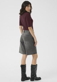 Gray denim shorts paired with a maroon top and black knee-high boots. The shorts have a loose fit and back pockets. Smooth, matte textures.
