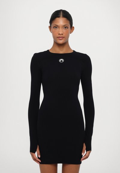 Černé dlouhé rukávy bodycon šaty s kulatým výstřihem, na hrudi s obvodovým bílým logem. Měkká, elastická tkanina s bočními rozparky.