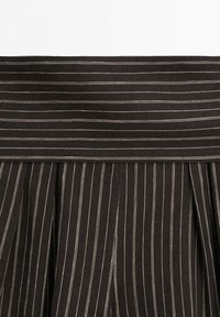 Black fabric with thin white vertical and horizontal pinstripes, featuring pleated details below a wide waistband.