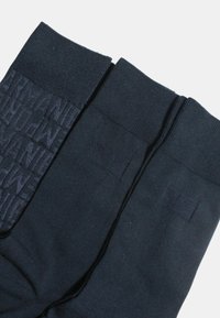 Dos pares de calcetines azul oscuro con puños acanalados. Uno tiene un patrón de logo texturizado y tonal, mientras que el otro presenta un acabado liso.