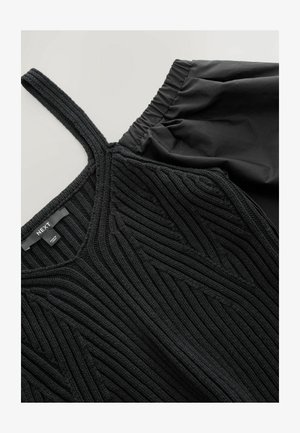 Sort strikket tanktop med tekstureret mønster og tynde stropper, parret med sorte culotter med elastisk talje.