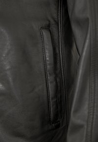 Schwarze Lederjacke mit elegantem Design, glatter Textur und einer vertikalen Reißverschlusstasche auf der linken Seite. Dezente Nähte.