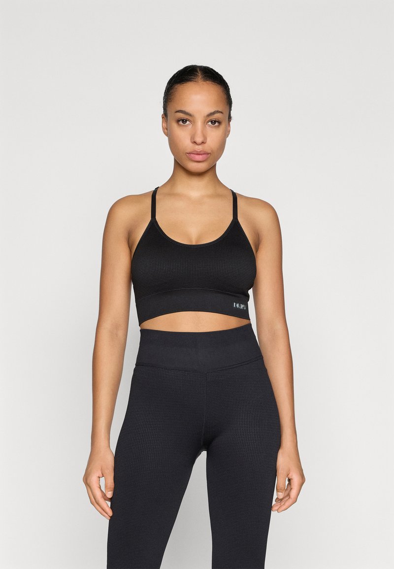 Svart ribbet sports-bh med bred kant og justerbare stropper, kombinert med høytalmede svarte leggings med et teksturert mønster.