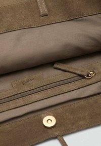 Pochette en suède marron et tissu avec un compartiment zippé, quincaillerie dorée et fermeture à bouton-pression ; finition douce et texturée.