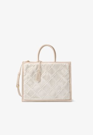 Sac fourre-tout rectangulaire beige avec un panneau avant en tissu doux matelassé, doubles poignées, bandoulière ajustable et une petite étiquette suspendue.
