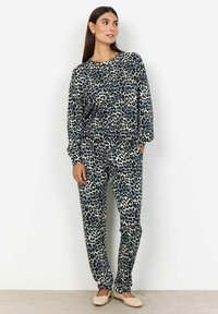Ensemble de loungewear en imprimé léopard dans des tons marine et crème, comprenant un haut à manches longues ample et un pantalon assorti à taille élastique.