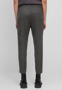Grijze, gestructureerde, taps toelopende broek met elastische tailleband, zijzak en achterzak, gecombineerd met zwarte enkellaarsjes.