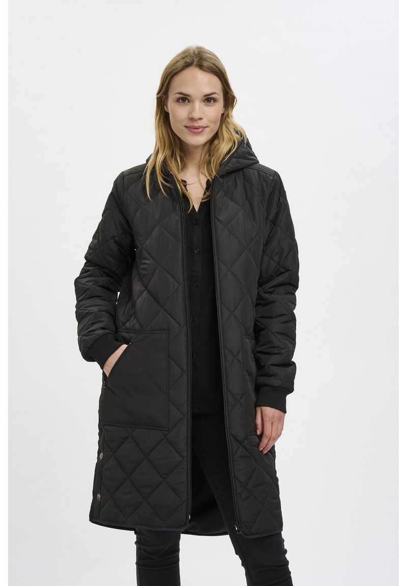 Manteau long matelassé noir avec capuche, doté de deux poches avant, de poignets côtelés et d'une fermeture éclair à l'avant. Tissu lisse et texturé.