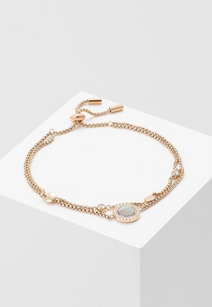 Delicate gold-tone adjustable bracelet with double chain, round mother-of-pearl center charm, and small clear crystal accents on white surface.