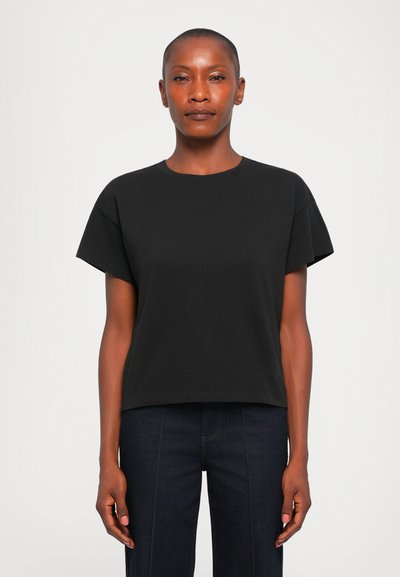 Μαύρη βαμβακερή μπλούζα t-shirt με κοντά μανίκια, στρογγυλή λαιμόκοψη, άνετη εφαρμογή και λεία υφή. Συνδυάζεται με σκούρα τζιν παντελόνια.