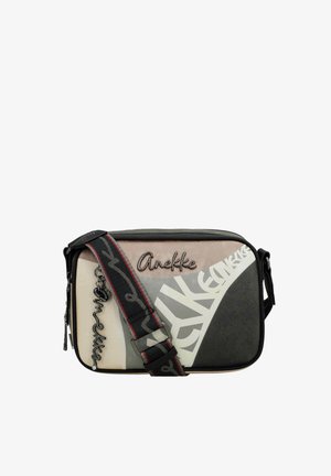 Bolso bandolera rectangular con paneles beige, gris y negro, de la marca "Anekke", decorado con un charm de logo desmontable y una correa ancha ajustable.