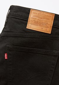 Zwarte denim jeans met een leren label met het merklogo en details. Inclusief een rood stoffen label aan de zijkant en een klassiek zakontwerp.