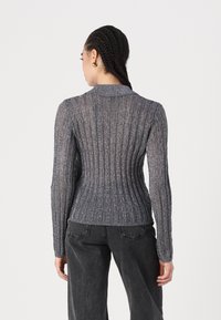 Halli ribakudum sweater, millel on peen sära. Omab pikad varrukad ja kraega kaelust, keha lähedane disain rõhutab vööd.