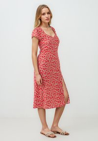 Rode bloemen midi-jurk met korte mouwen, een V-hals en een zij-split. Heeft kleine witte bloemen op een levendige achtergrond. Lichtgewicht stof.