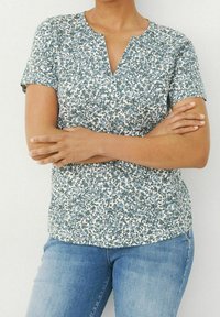 Blusenshirt mit kurzen Ärmeln und floralem Design, V-Ausschnitt, grün-blauem Muster auf weißem Hintergrund, aus weichem Stoff und lockerer Passform.