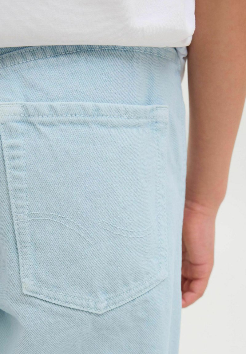 Ljusblå denimjeans med en bakficka som har diskreta sömnadsdetaljer. Tygmaterialet har en slät textur och en avslappnad design.