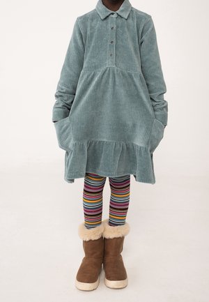 Jasnoniebieska sukienka z korduroy z kołnierzykiem, długimi rękawami i falbaniastym dołem. W połączeniu z wielokolorowymi rajstopami w paski i brązowymi botkami z futerkiem.